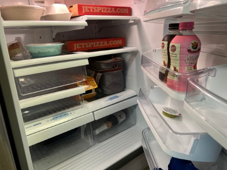 An and half-empty refrigerator with food in plastic containers